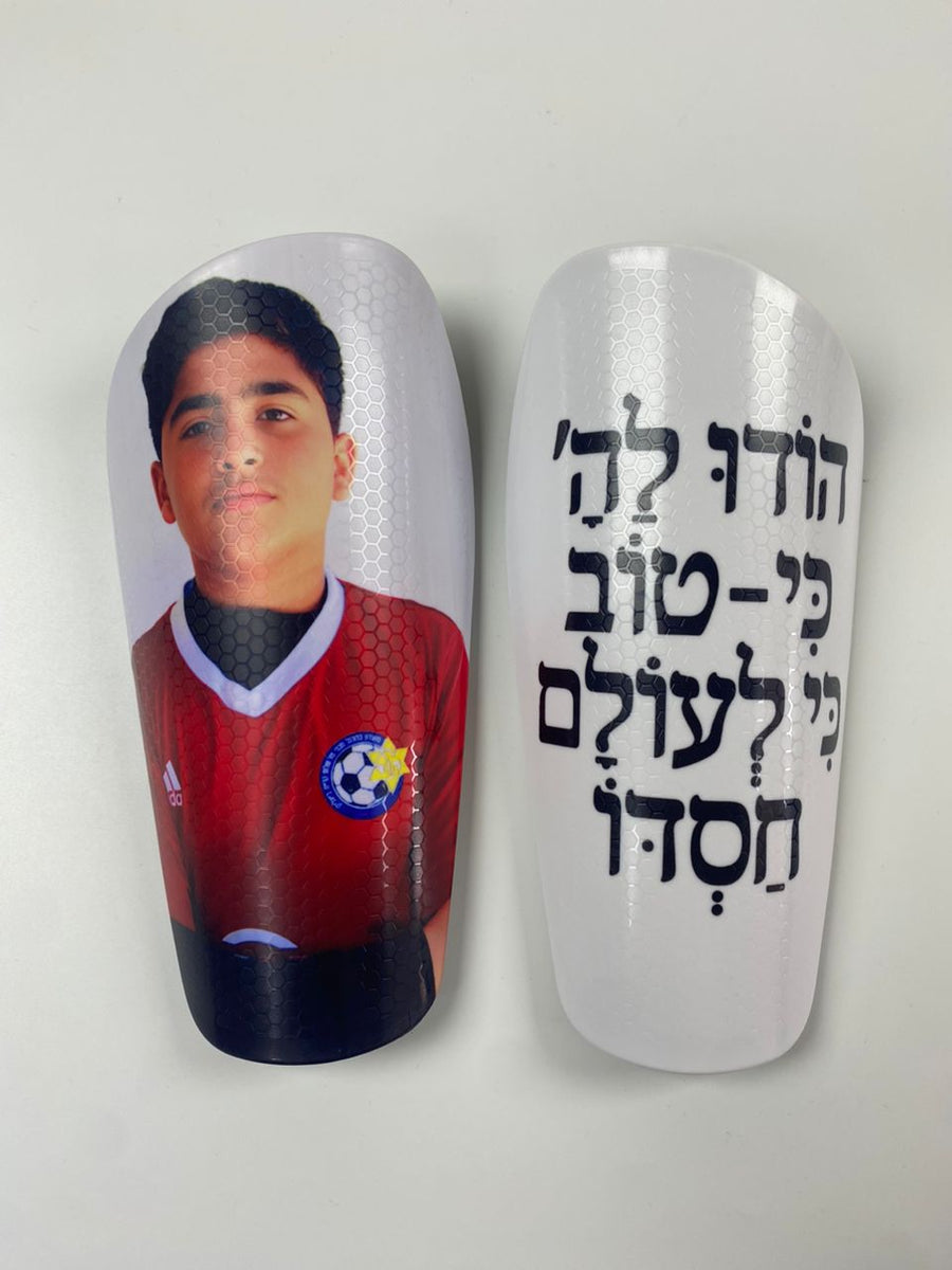 Custom shin guards with a player portrait and Hebrew Hodu LaHashem verse