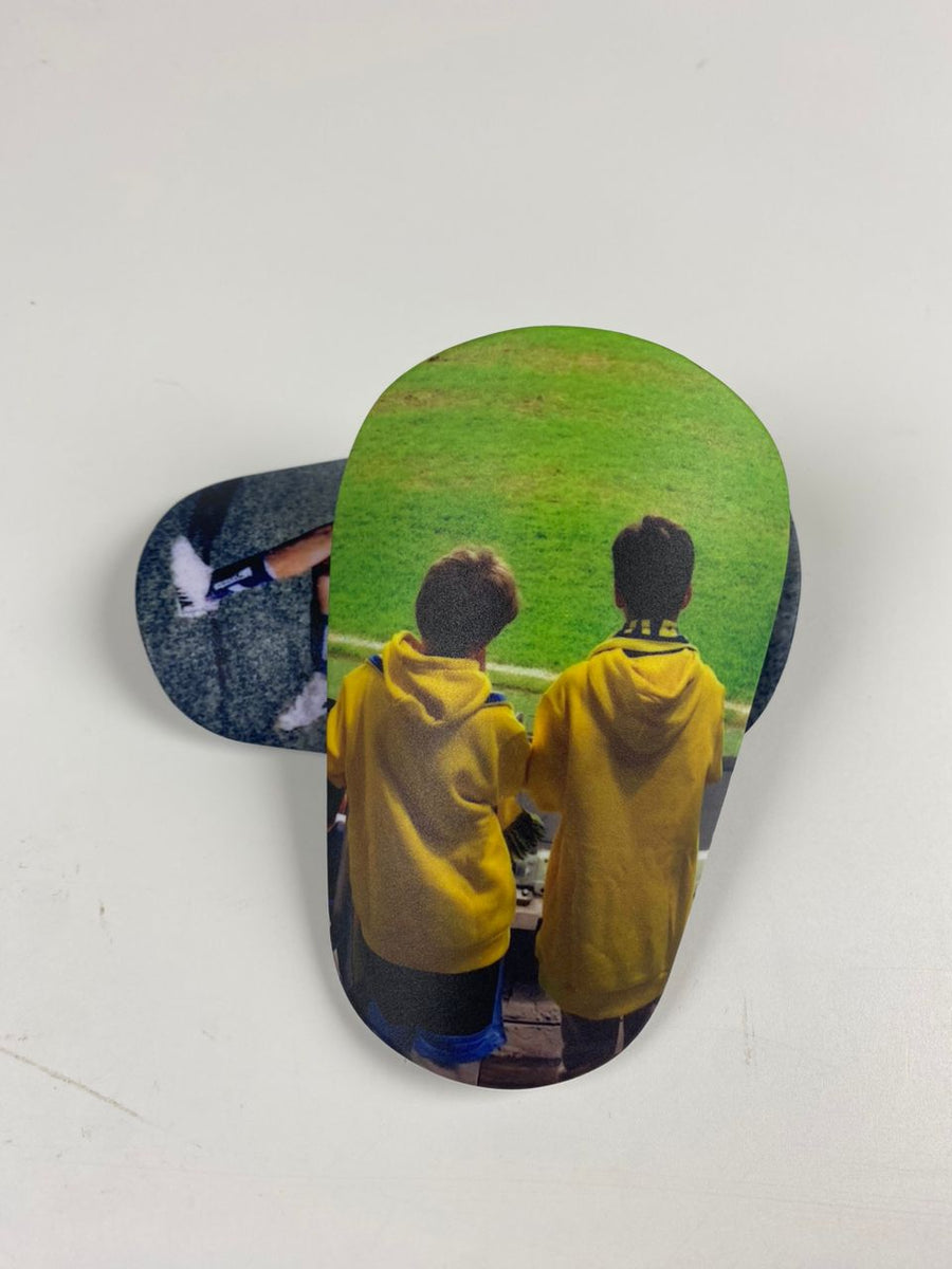 Custom shin guards with two children in yellow hoodies watching a field